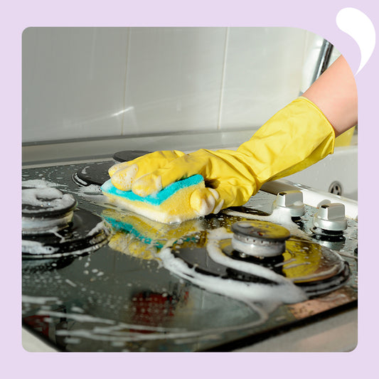 one hand with a glove is wiping the stove top