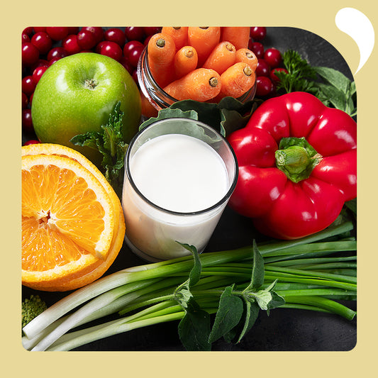 a cup of milk surrounded by fruits and vegetables