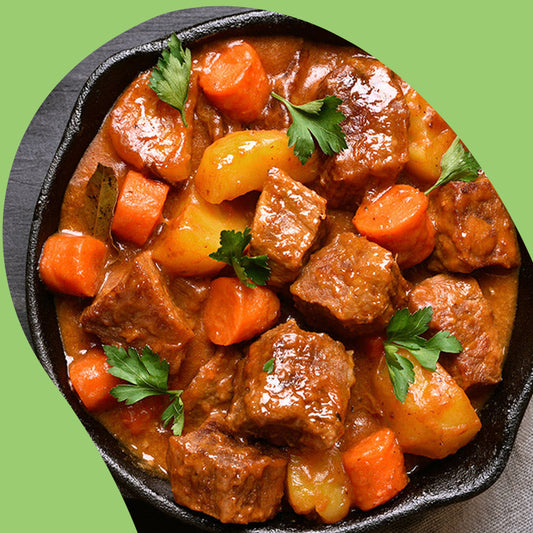 plate of beef stew and potatoes with a piece being picked up by a spoon