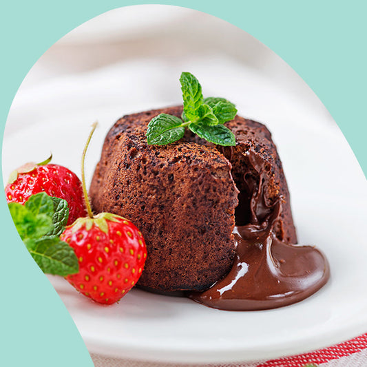 molten chocolate lava cake with hot fudge sauce pouring out next to two strawberries