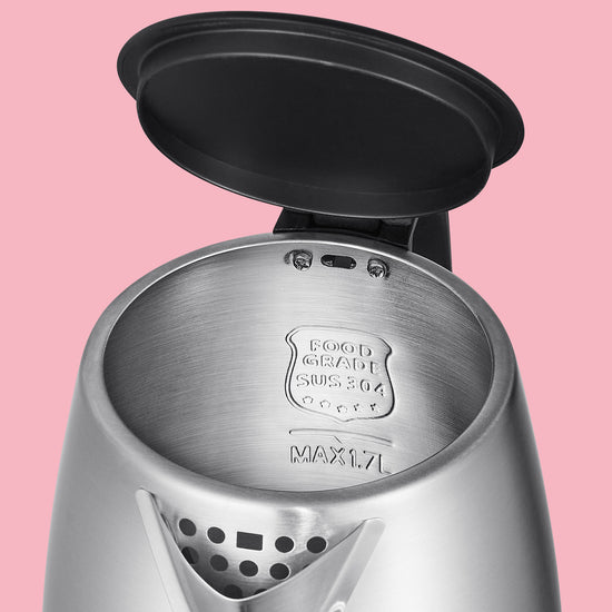 one hand holds a strainer on the spout of the kettle