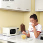 a girl drink a cup of tea with popcorn next to microwave